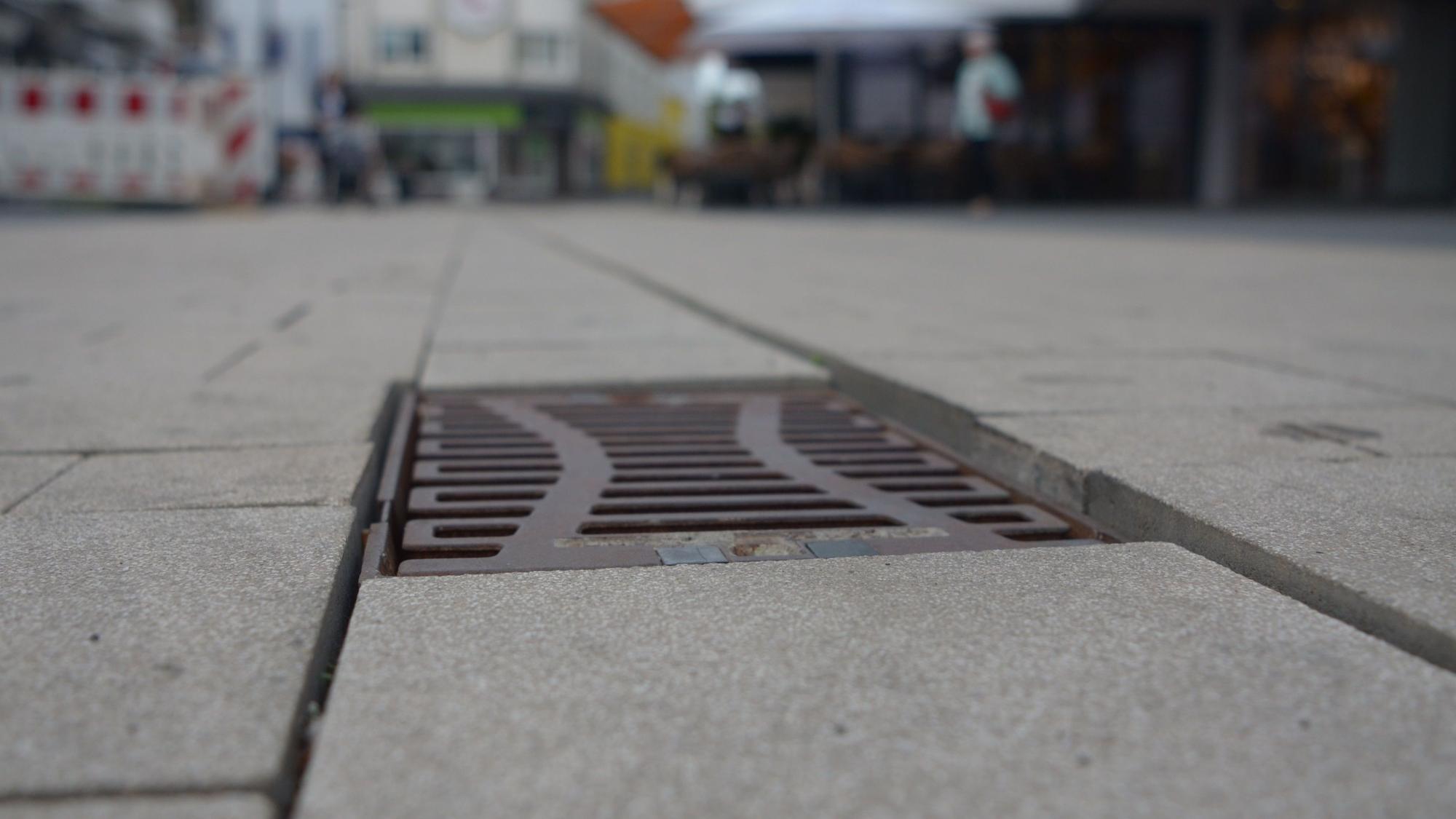 An einem Gully in der Berliner Straße wurden die Pflastersteine unterschiedlich hoch verlegt, sodass Stolperkanten entstanden sind.