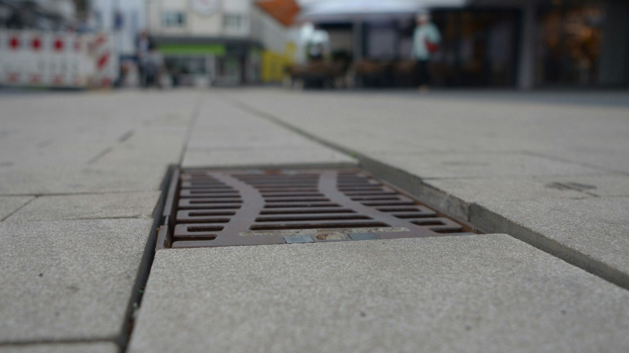 An einem Gully in der Berliner Straße wurden die Pflastersteine unterschiedlich hoch verlegt, sodass Stolperkanten entstanden sind.
