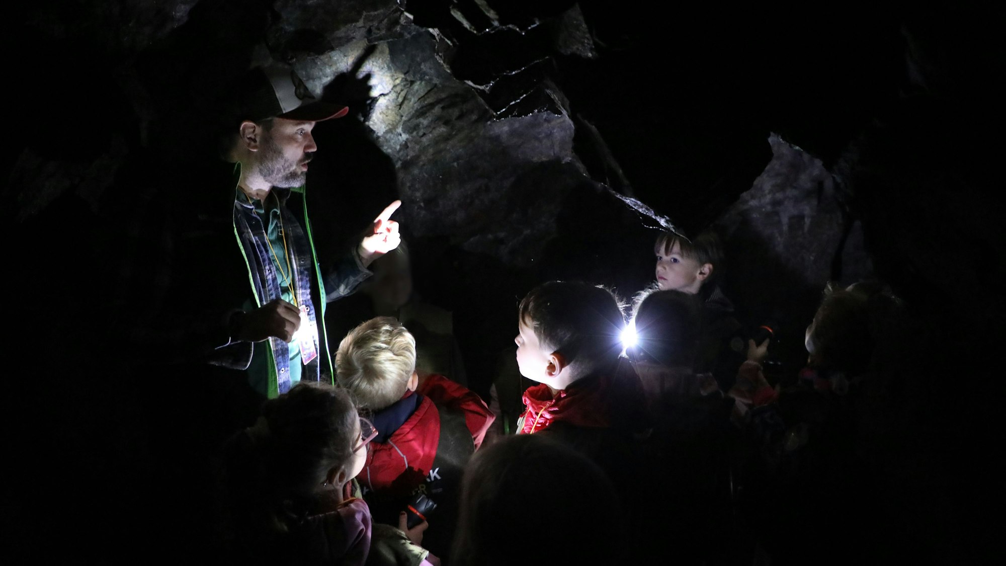 Ein Mann steht mit Kindern in einer Höhle.