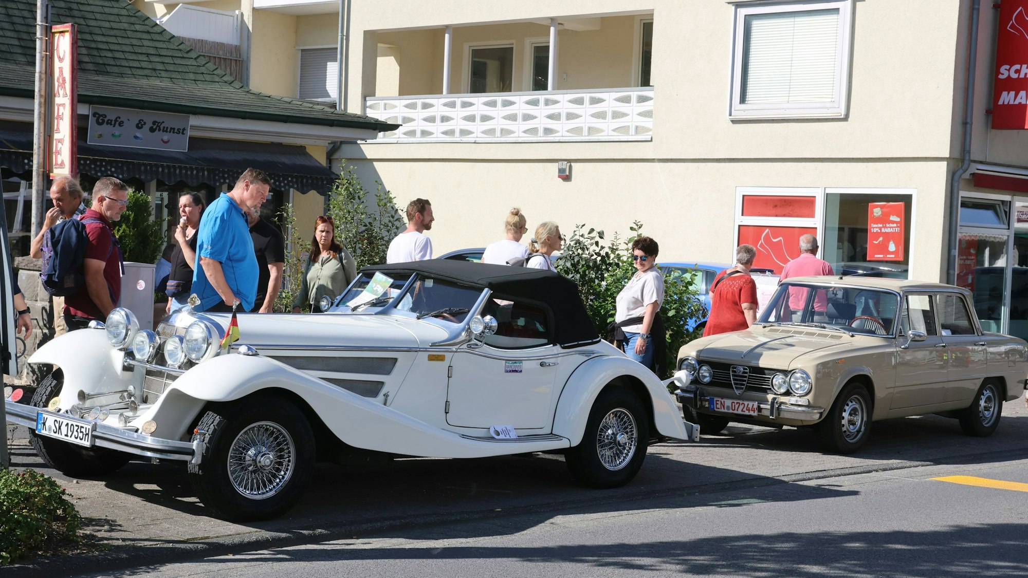 Das Foto zeigt mehrere Oldtimer und Besucher des Festes