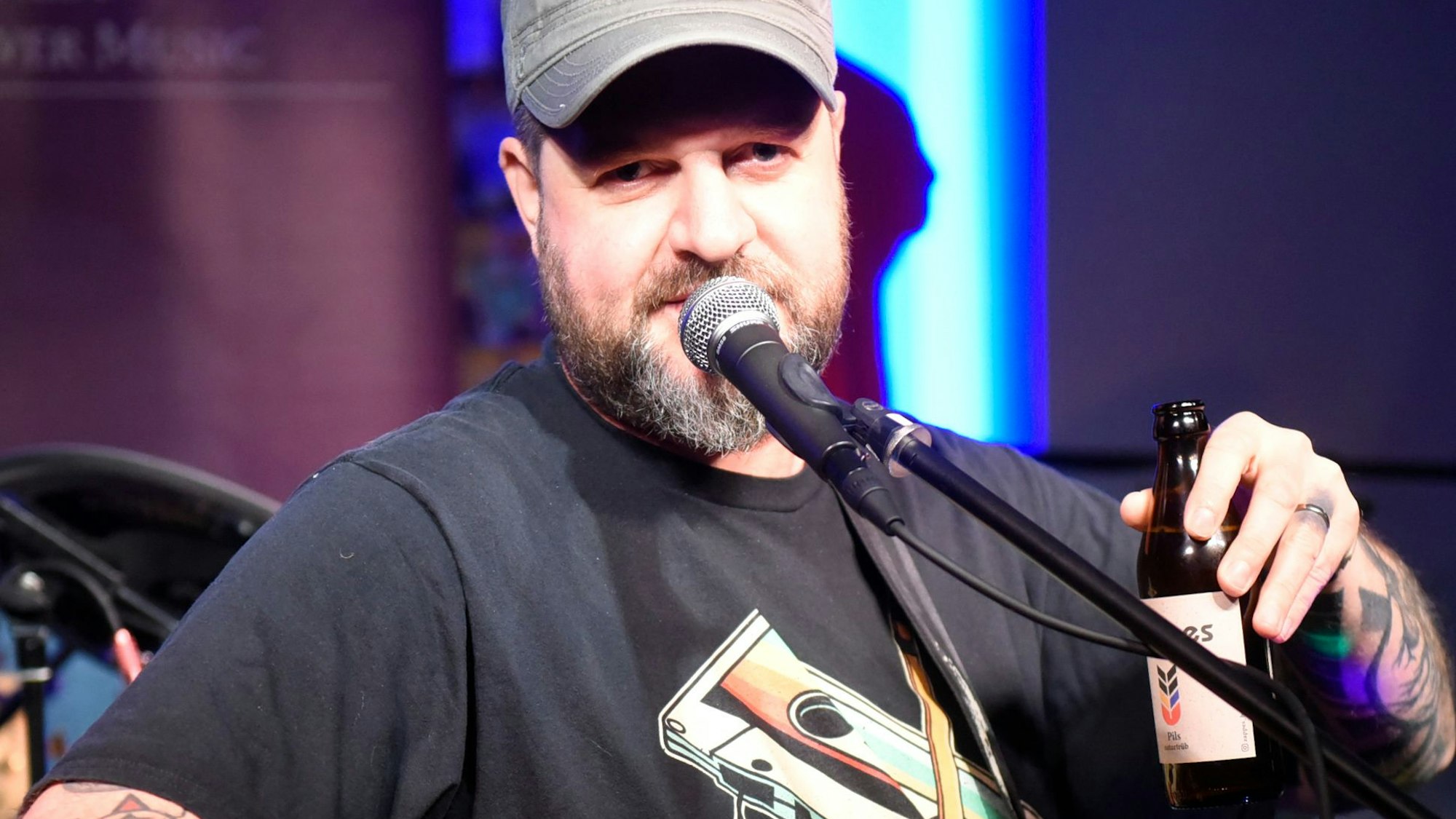 Der Punk-Musiker Butterwegge mit einer Gitarre und einem Bier.