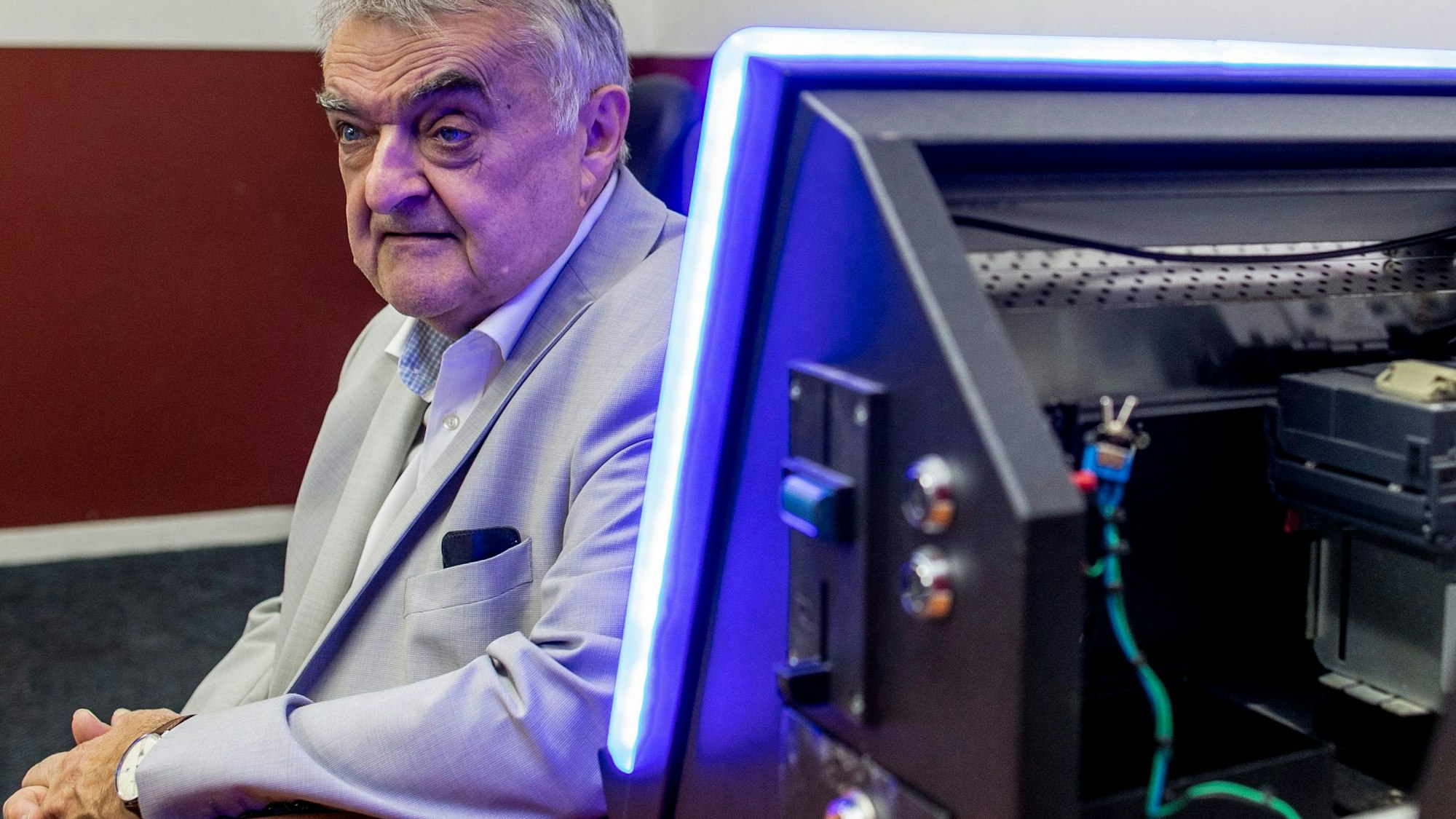 Herbert Reul sitzt bei einer Razzia im Duisburger Norden an einem Spieltisch, auf dem ein illegaler Geldspielautomat steht.