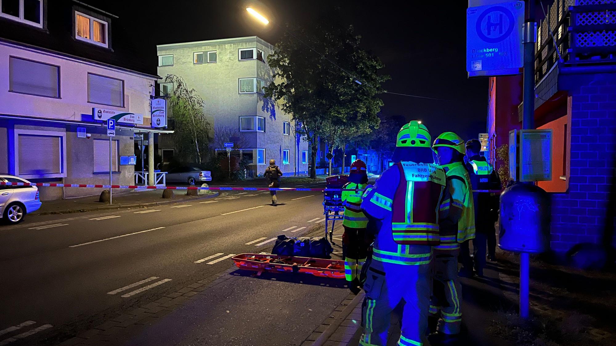Ein 32 Jahre alter Mann hat erst eine 29 Jahre alte Frau niedergestochen und ist dann auf ein Dach geflüchtet, von wo aus er Polizisten mit Dachziegeln bewarf. Spezialeinsatzkräfte überwältigten ihn. Feuerwehrleute leuchten aus sicherer Entfernung aus. In der Mitte geht eine Spezialeinsatzkraft auf das Haus zu.