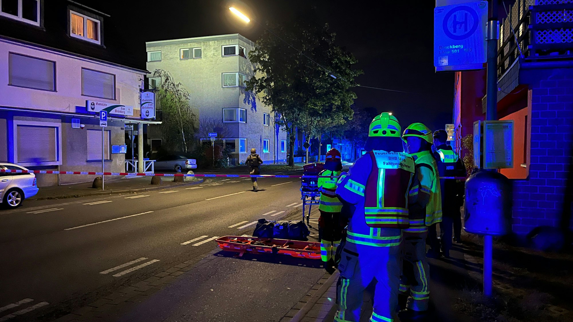 Ein 32 Jahre alter Mann hat erst eine 29 Jahre alte Frau niedergestochen und ist dann auf ein Dach geflüchtet, von wo aus er Polizisten mit Dachziegeln bewarf. Spezialeinsatzkräfte überwältigten ihn. Feuerwehrleute leuchten aus sicherer Entfernung aus. In der Mitte geht eine Spezialeinsatzkraft auf das Haus zu.
