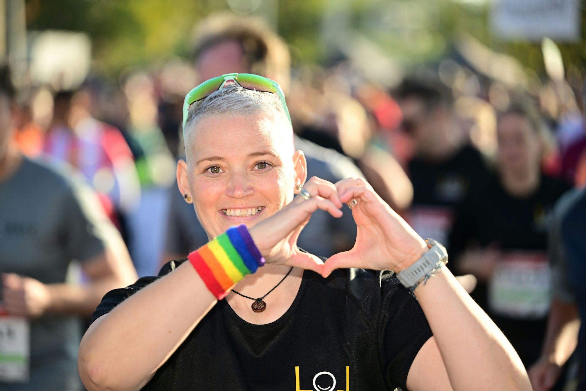 Eine Läuferin des Marathons formt mit den Händen ein Herz und lächelt.