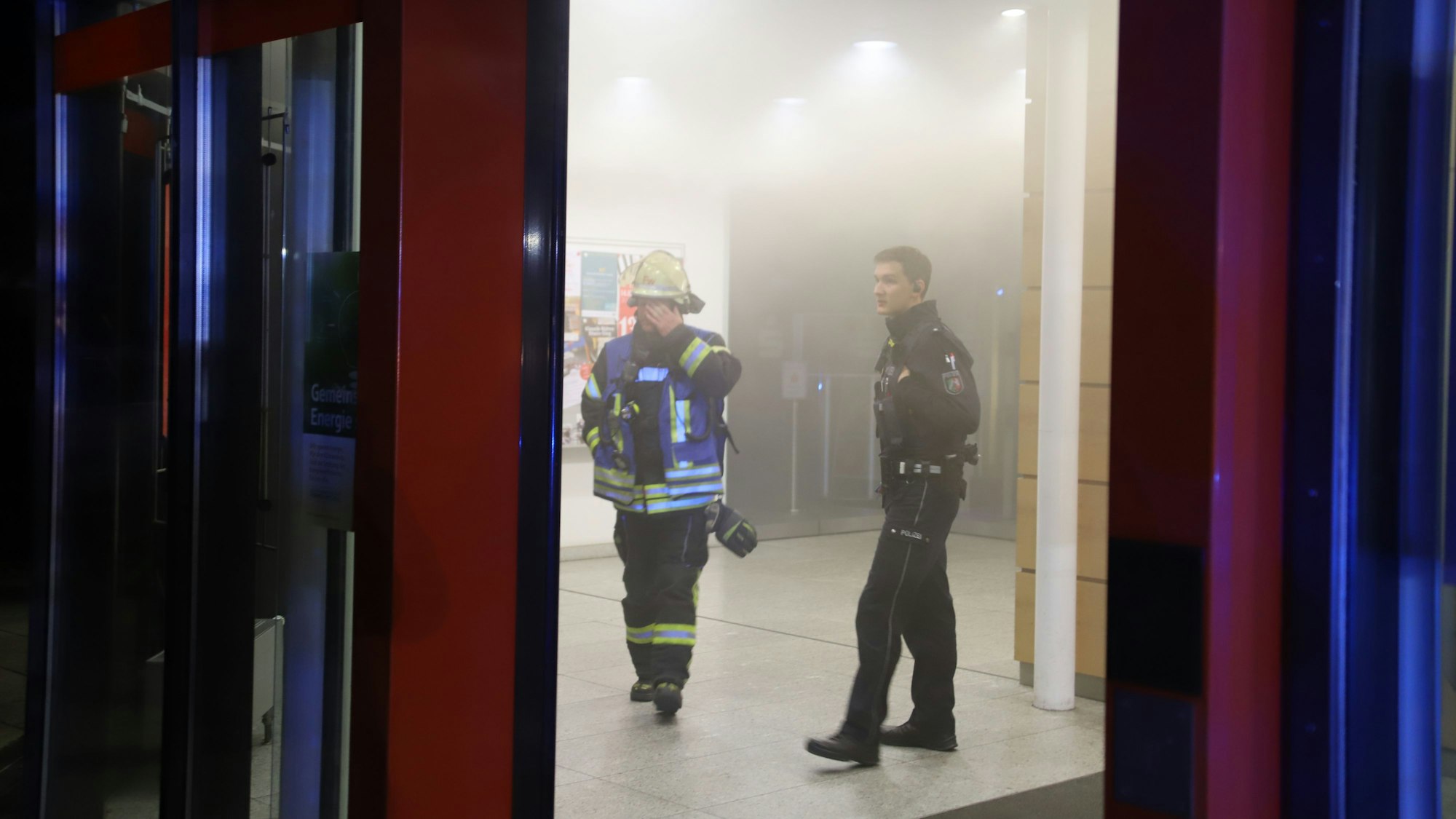 Nach einigen Minuten konnten Polizei und Feuerwehr den Vorraum betreten, Der Feuerwehrmann und der Polizist suchten nach Beschädigungen in dem noch leicht verrauchten Vorraum, entdeckten aber keine.