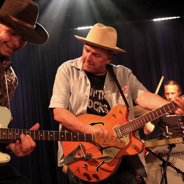 Zwei Musiker von Hillbilly Deluxe mit Gitarre und Cowboy-Hüten.