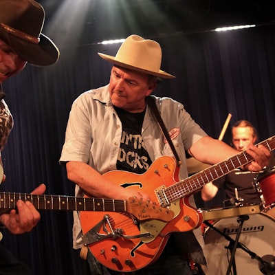 Zwei Musiker von Hillbilly Deluxe mit Gitarre und Cowboy-Hüten.