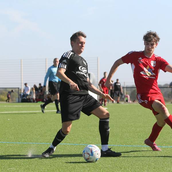 Ein Fußballspieler führt den Ball, von der Seite kommt ein Gegner angelaufen.