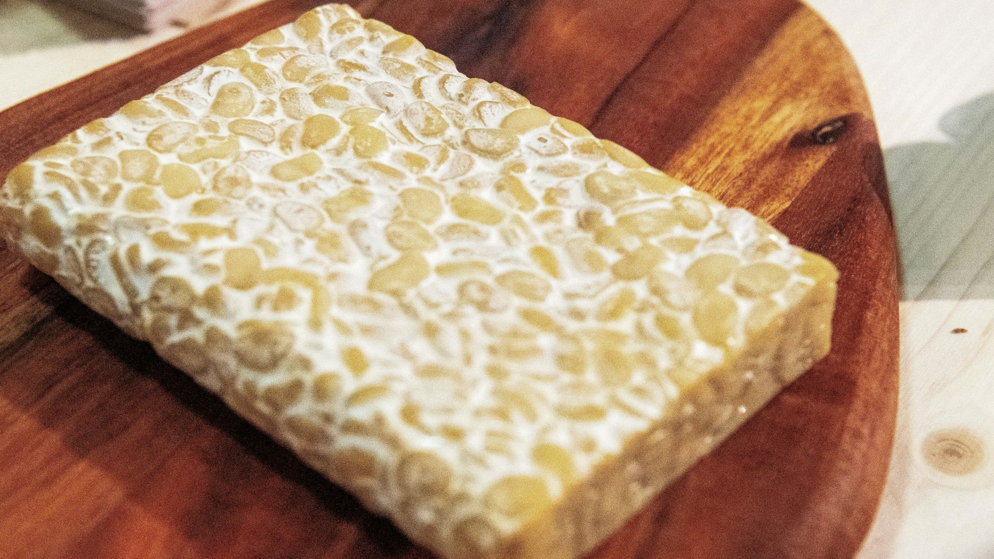 Ein Block Tempeh liegt auf einem Holzbrett