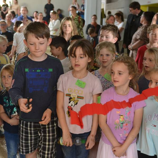 Schüler schneiden ein rotes Band zur Wiedereröffnung der Räume durch.