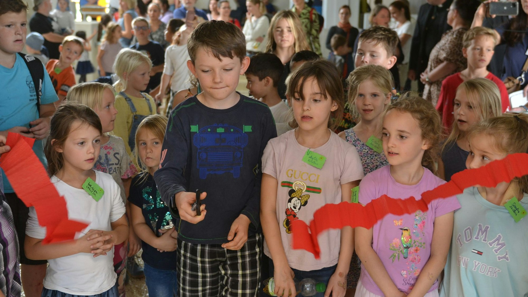 Schüler schneiden ein rotes Band zur Wiedereröffnung der Räume durch.