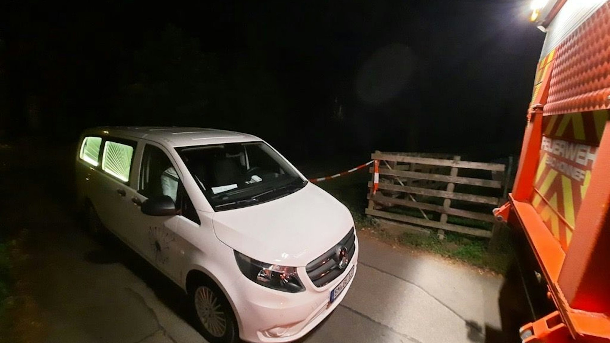 Ein Auto steht hinter einem Feuerwahrfahrzeug im Dunkeln.