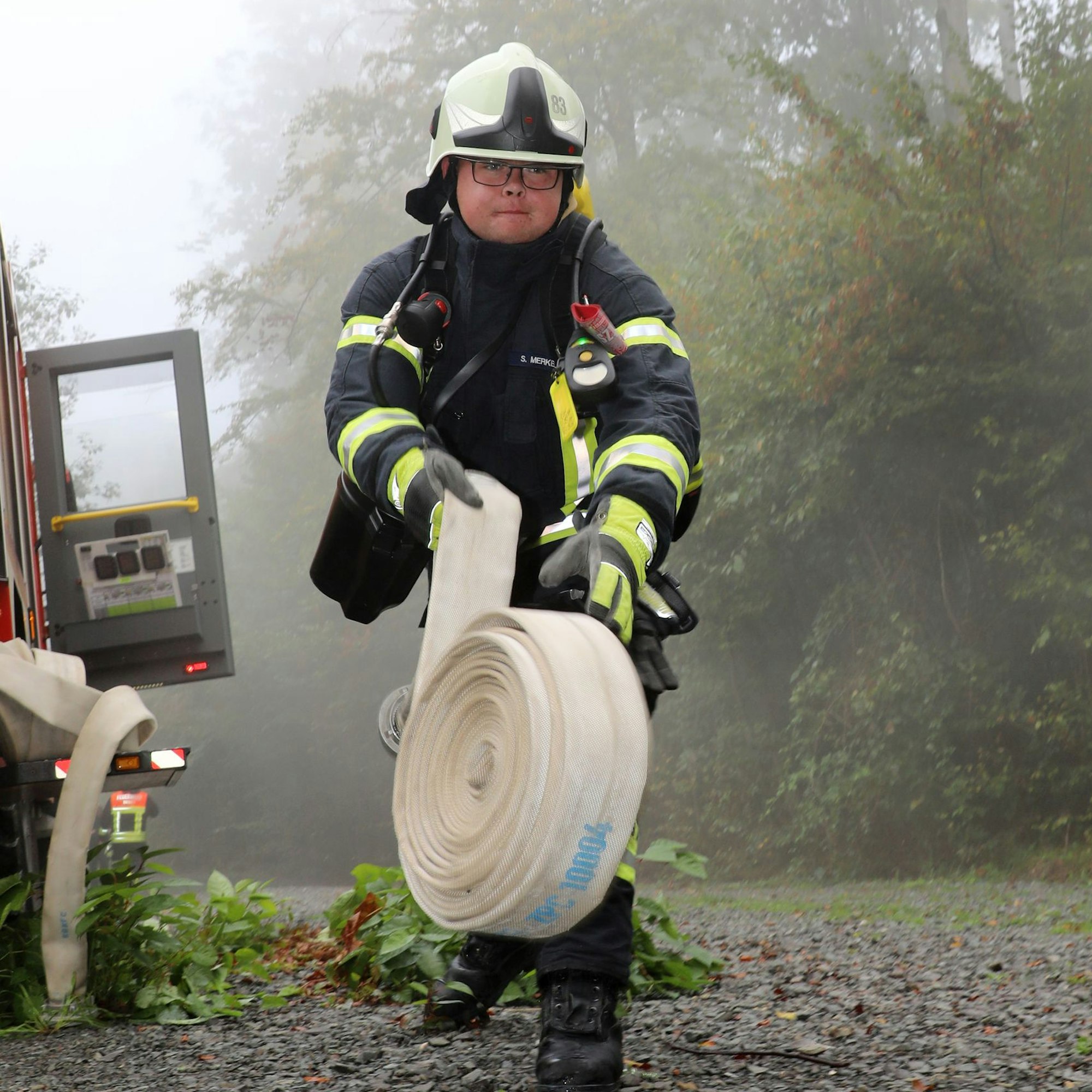 Ein Feuerwehrmann rollt einen Schlauch aus.