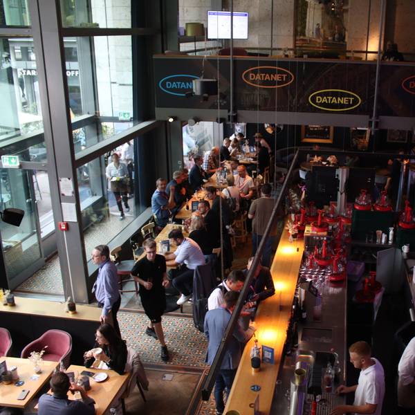 Menschen unterhalten sich in Kneipenstimmung. Das Datanet-Logo prangt an den Wänden.