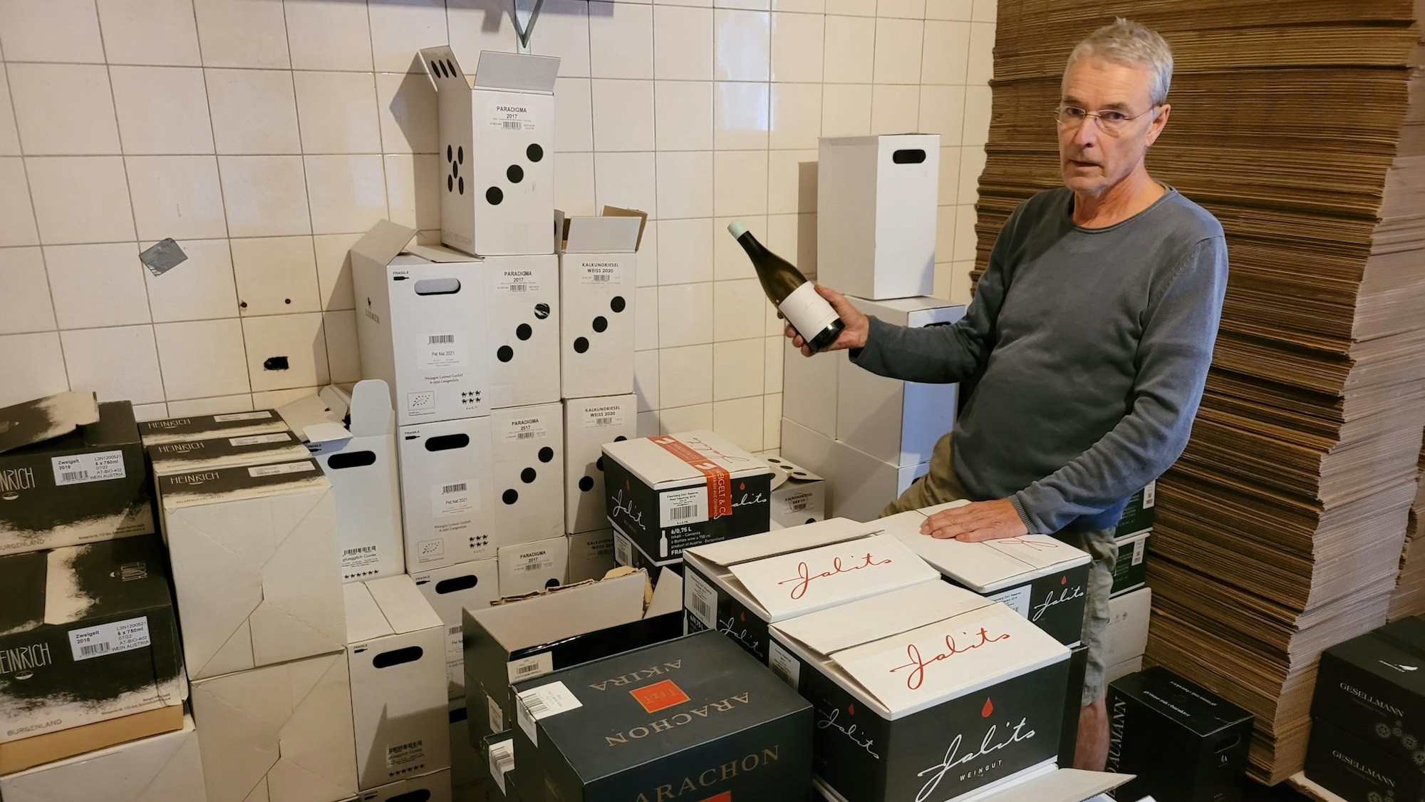 Das Foto zeigt den Online-Weinhändler in einem seiner Lagerräume, um ihn herum stapeln sich Weinkartons.