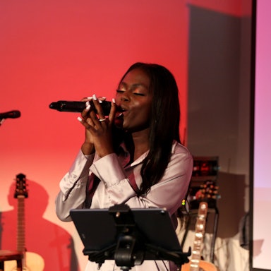 Eine Frau singt auf einer Bühne in ein Mikrofon.