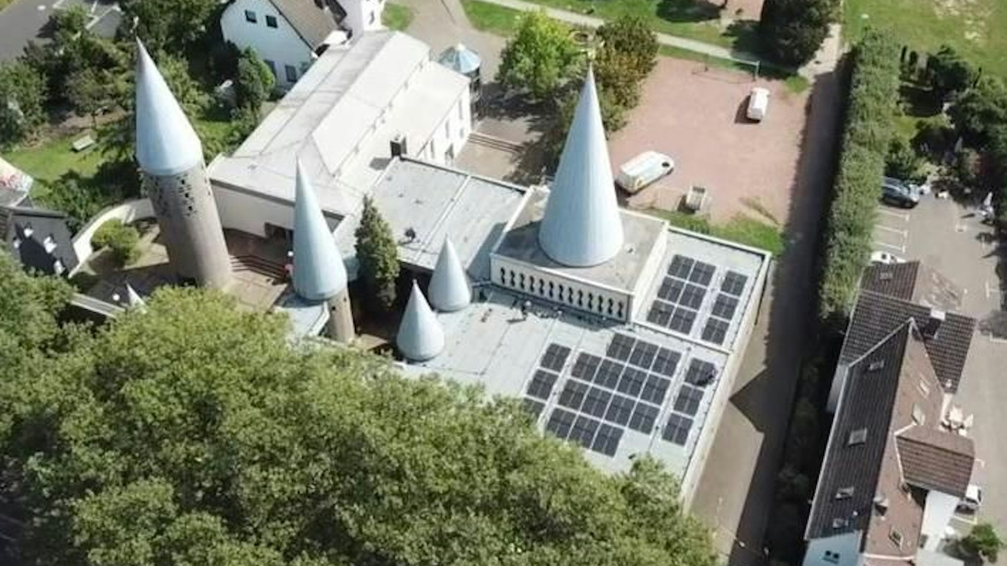 Das Foto ist aus der Luft aufgenommen: Man sieht die Solarmodule in Schwarz auf einem Teil des Kirchendachs. Sie sind platziert vor den fünf unterschiedlich großen drei Kirchtürmen.