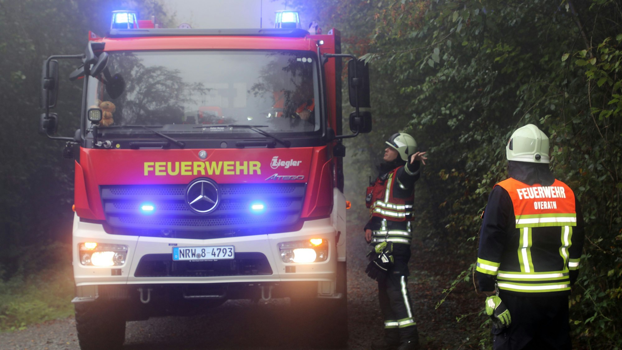 Ein Feuerwehrmann erklärt dem Fahrer eines Feuerwehrfahrzeug, wo er hinfahren soll und weist ihm den Weg.