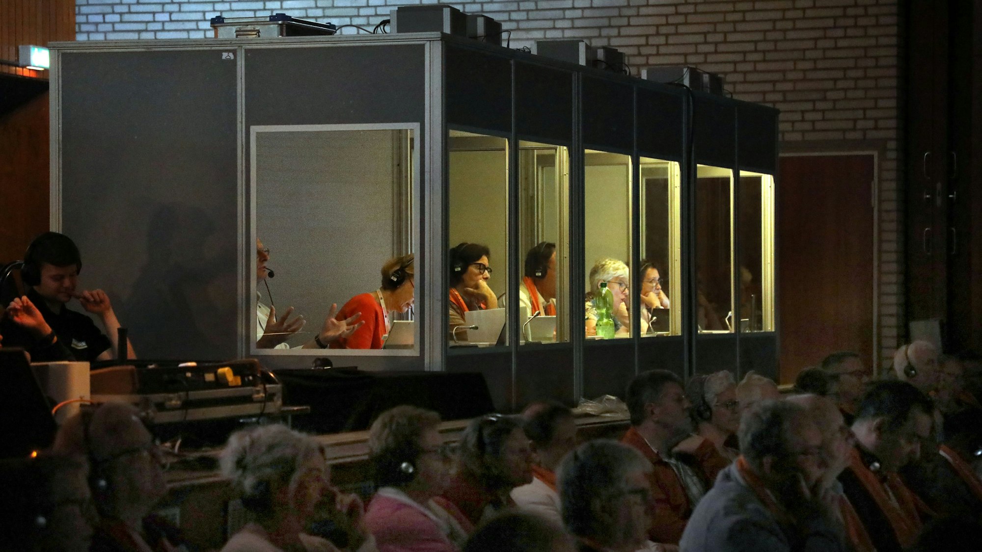 In Kabinen sitzen Dolmetscher und übersetzen eine Podiumsdiskussion simultan.