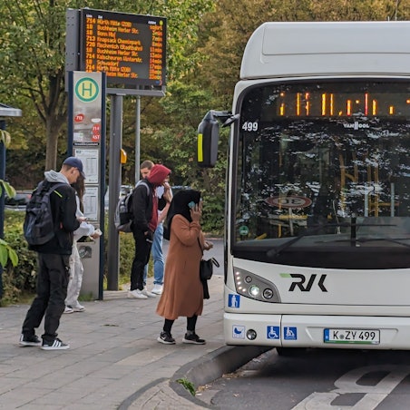 Ein Bus steht an einer Bushaltestelle, an der Fahrgäste warten.