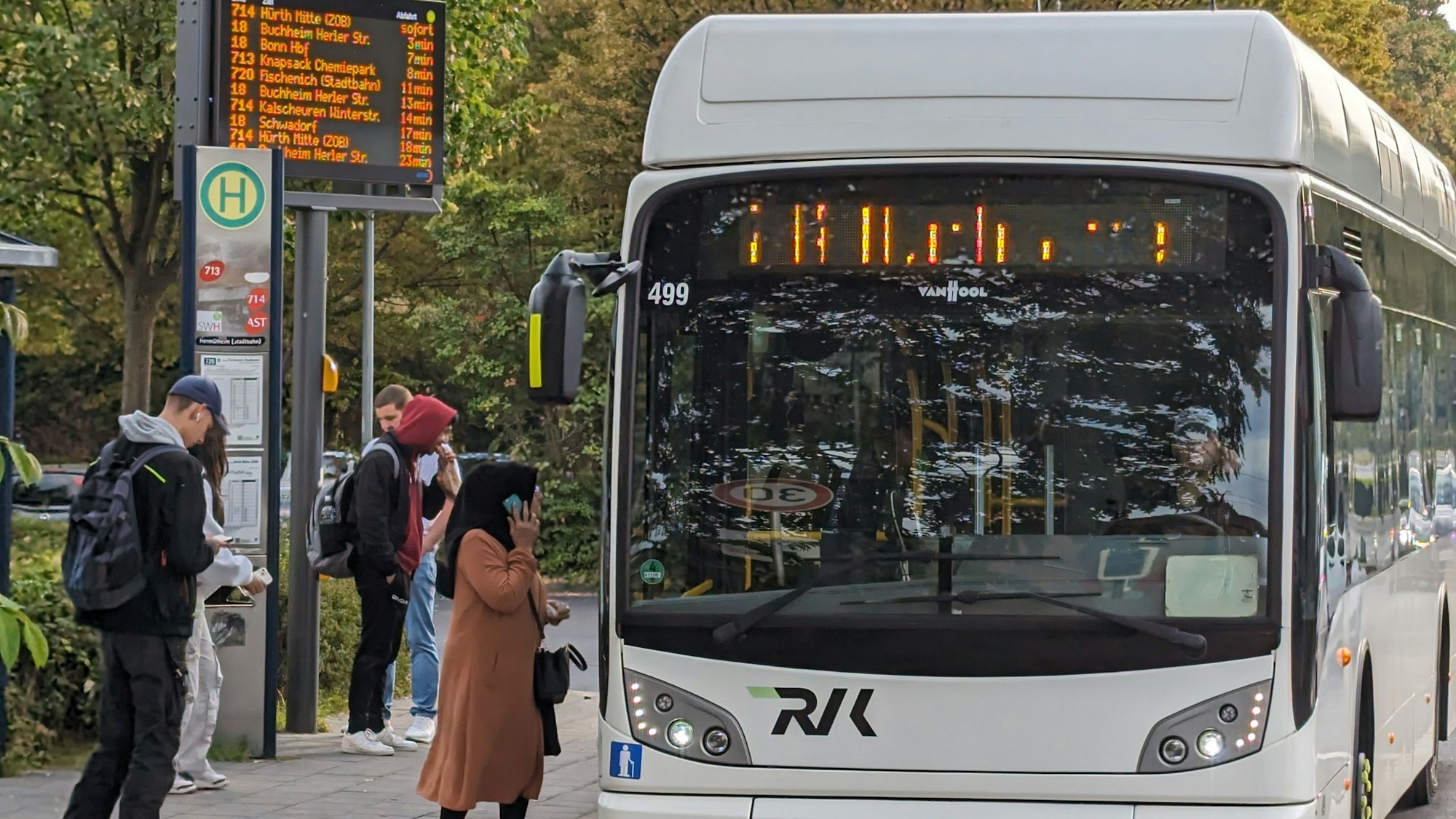 Ein Bus an einer Bushaltestelle in Hürth-Hermülheim, an der Fahrgäste warten.