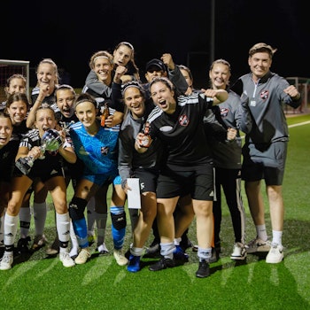 Eine Frauenfußballmannschaft jubelt über den Pokalsieg.