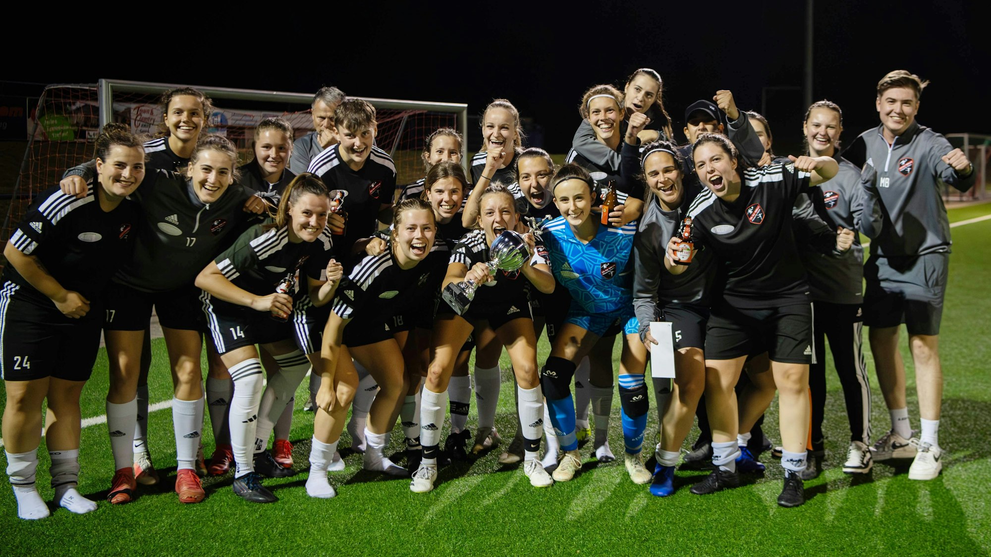 Eine Frauenfußballmannschaft jubelt über den Pokalsieg.