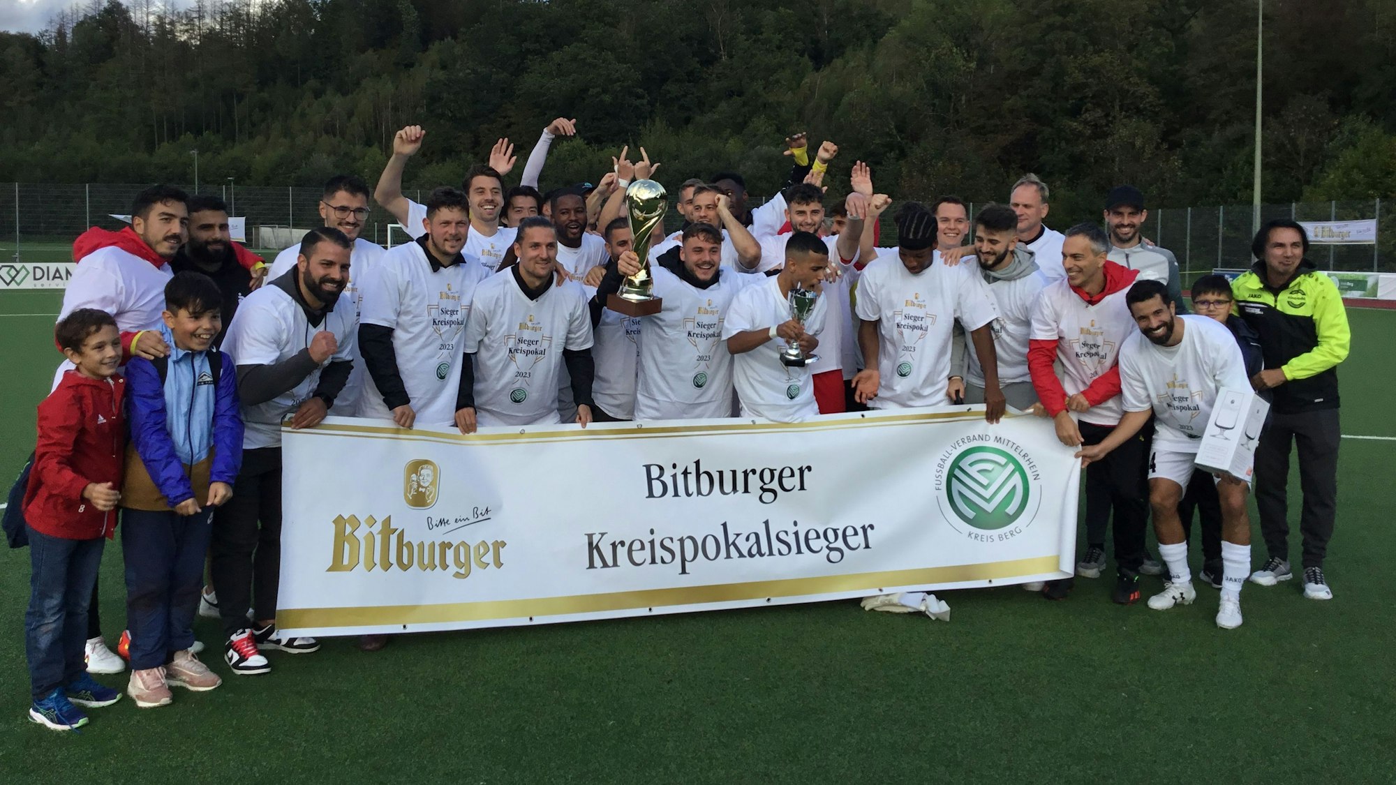 Die Mannschaft von Eintracht Hohkeppel feiert hinter einem Banner mit der Aufschrift Bitburger Kreispokalsieger.