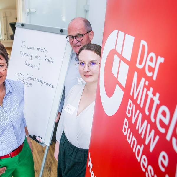 Blick auf drei Menschen vor einer Leinwand.