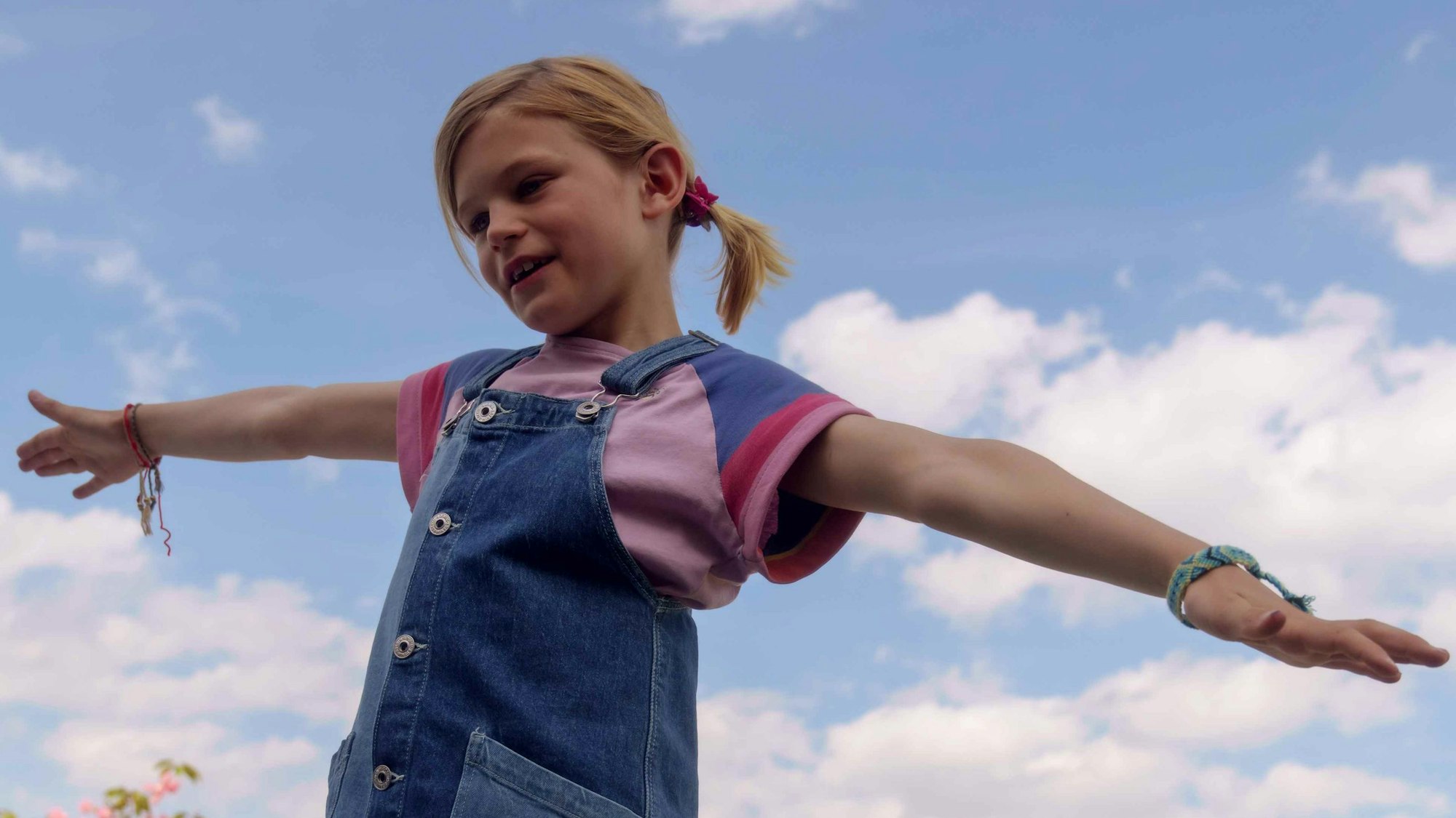 Ein Mädchen steht mit ausgebreiteten Armen.