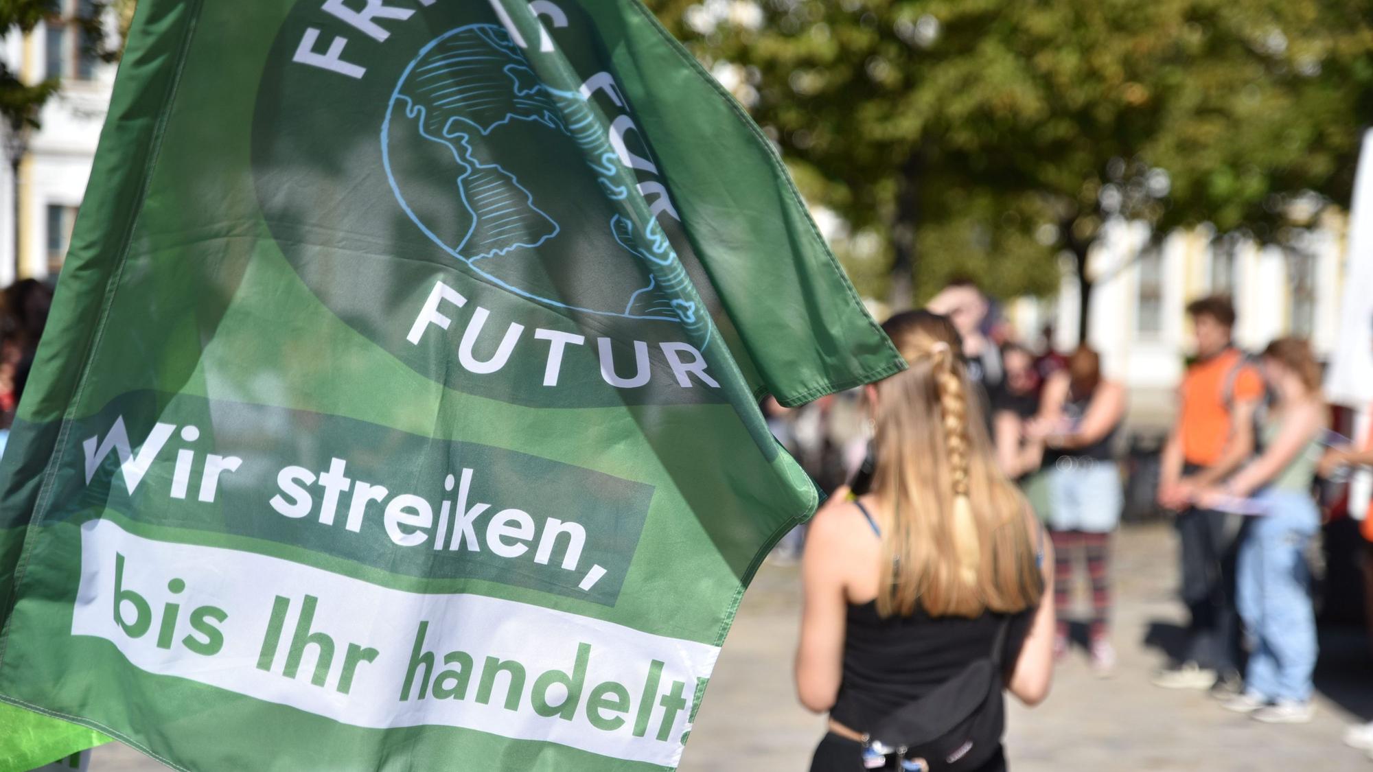 Eine Rednerin spricht zum „Klimastreik“ von Fridays for Future auf dem Domplatz in Magdeburg. Im Vordergrund ist eine Flagge der Klimaaktivisten