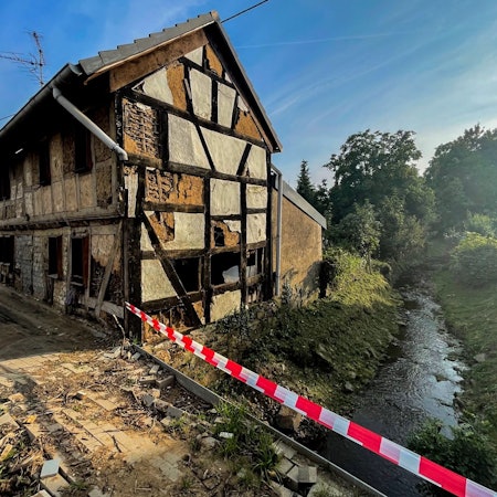 Das Bild zeigt ein zerstörtes Fachwerkhaus neben dem Steinbach mitten in Schweinheim.