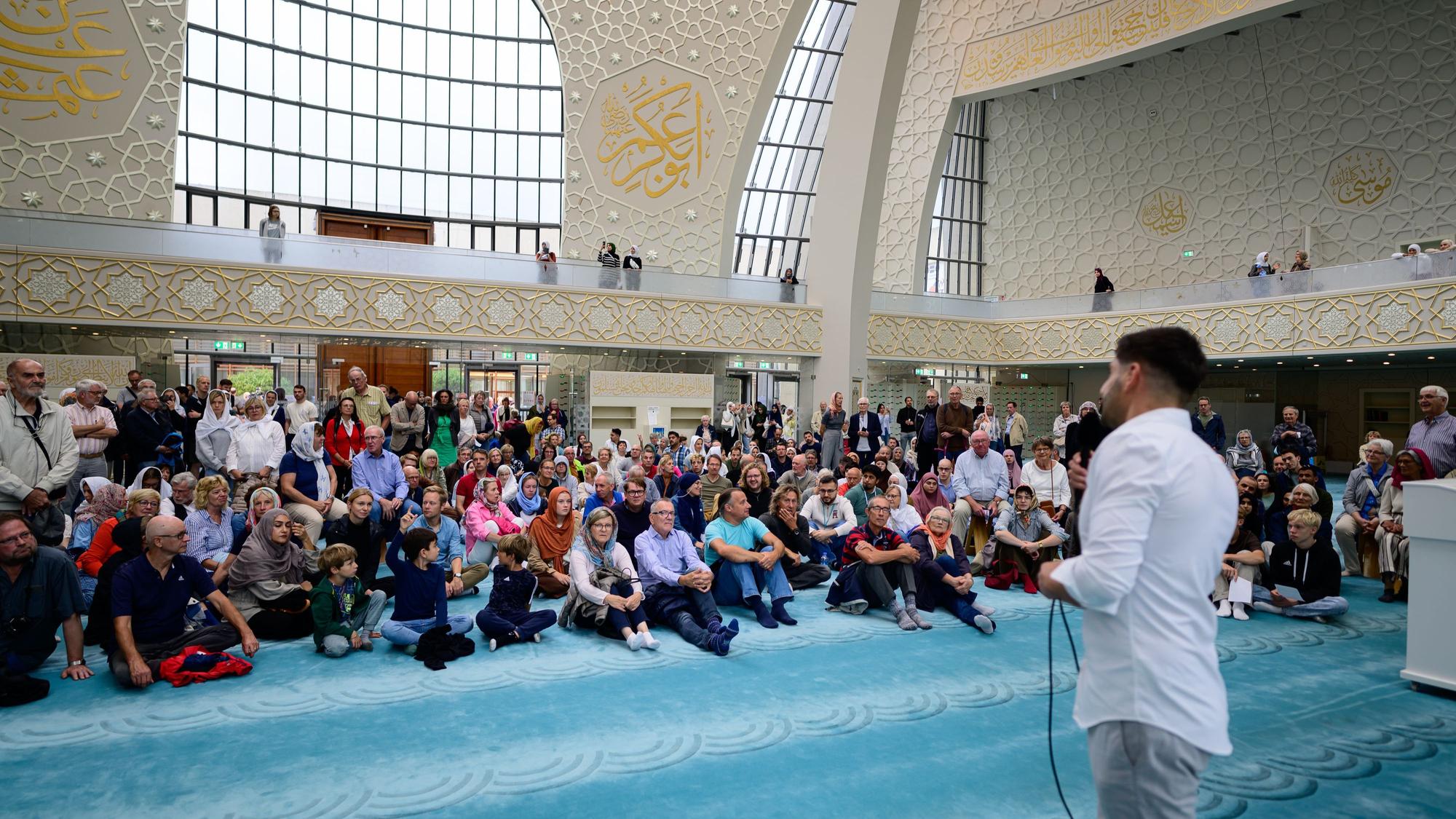 Menschen hören Erklärungen in der Zentralmoschee zu.