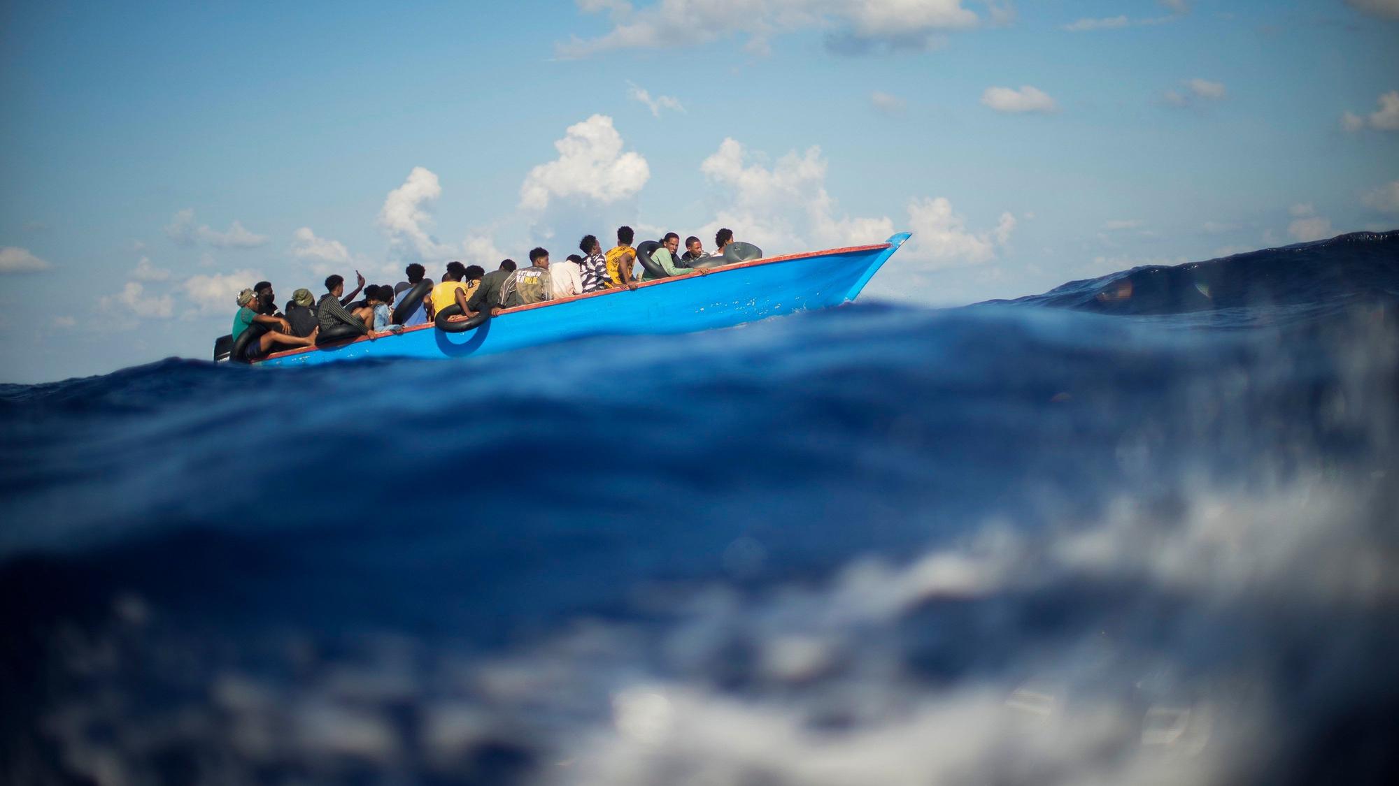 Flüchtende sitzen auf einem Holzboot und fahren über das Mittelmeer, die Aufnahme ist kurz vor der italienischen Insel Lampedusa entstanden. (Archivbild)