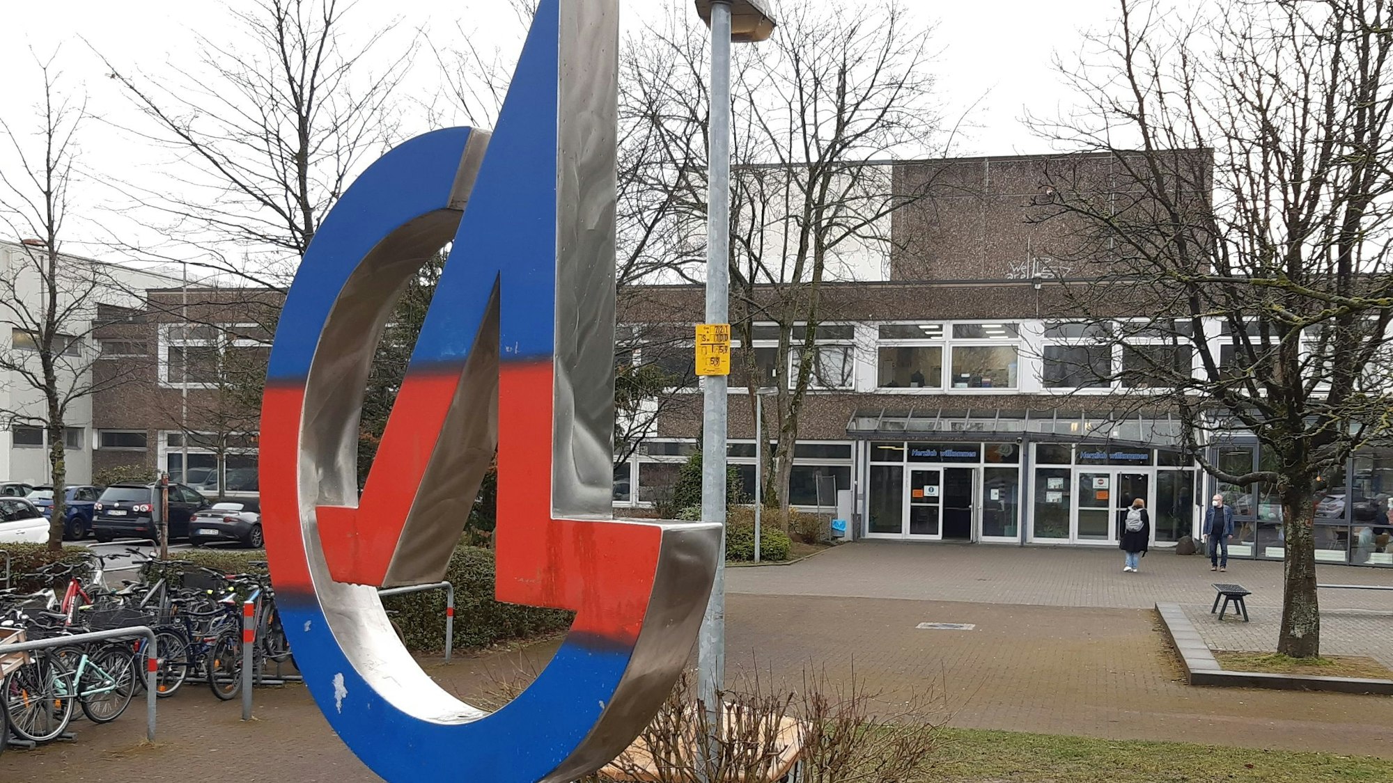 Eine Schule, im Vordergrund das blau-rote Logo.