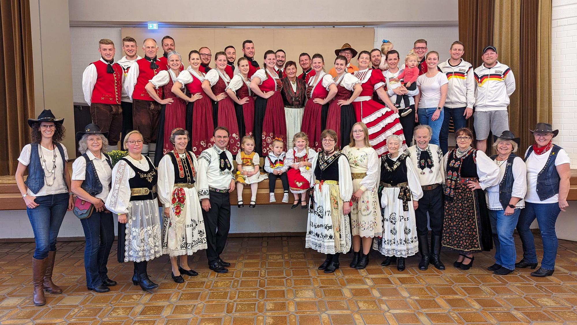 Rund 50 Tänzerinnen und Tänzer in bunten Trachten posieren für ein Gruppenbild.