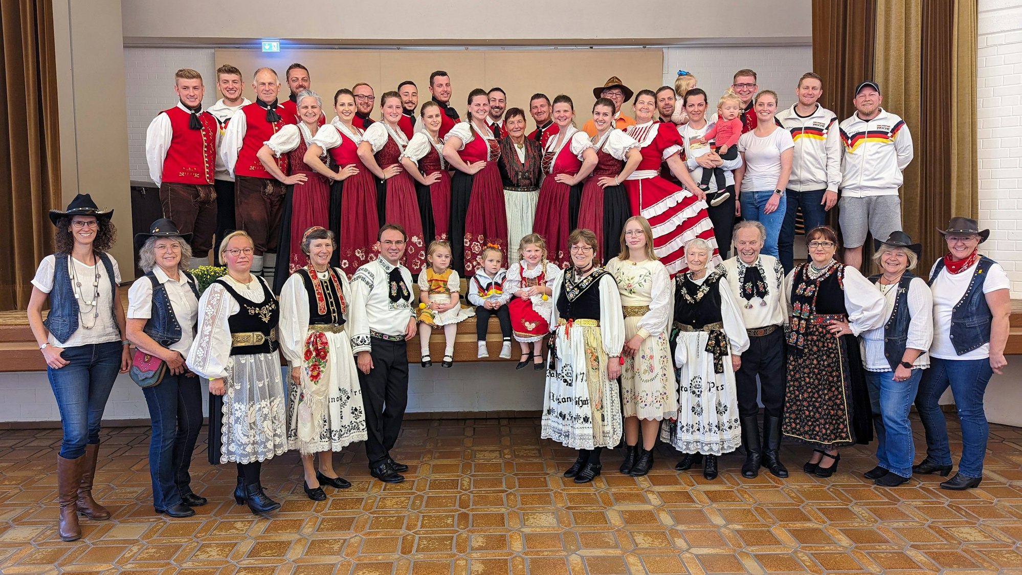 Rund 50 Tänzerinnen und Tänzer in bunten Trachten posieren für ein Gruppenbild.
