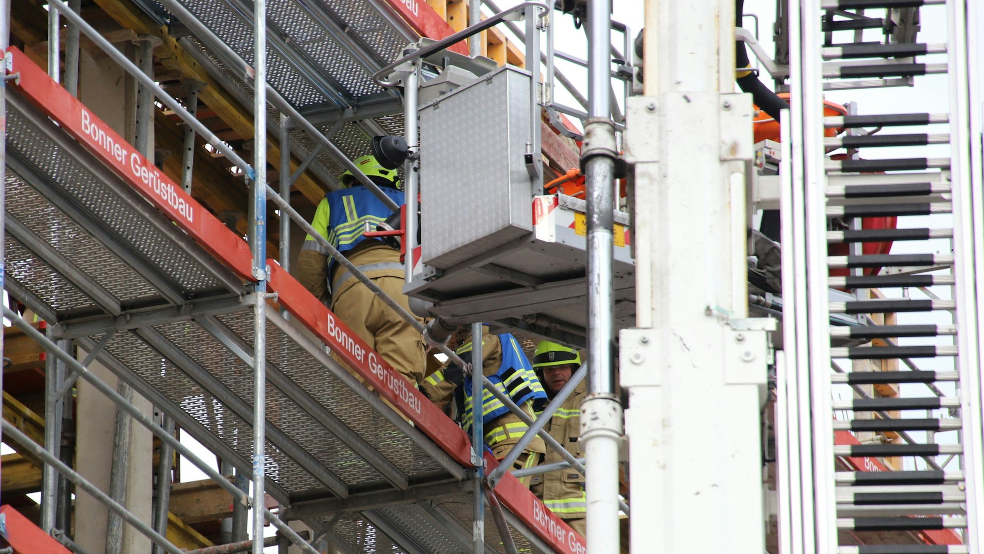 Auf der Baustelle des neuen Gerichtsgebäudes für die Cum-Ex-Prozesse ist ein 64 Jahre alter Bauarbeiter schwer verletzt worden. Feuerwehrmänner schieben ihn auf einer Schlleifkorbtrage auf den Korb des Teleskopmasts.