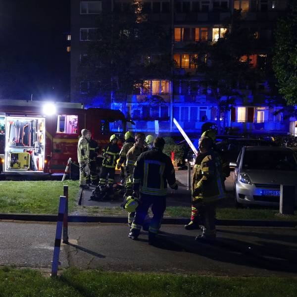 Feuerwehrleute stehen vor dem betroffenen Hochhaus in Niederpleis.