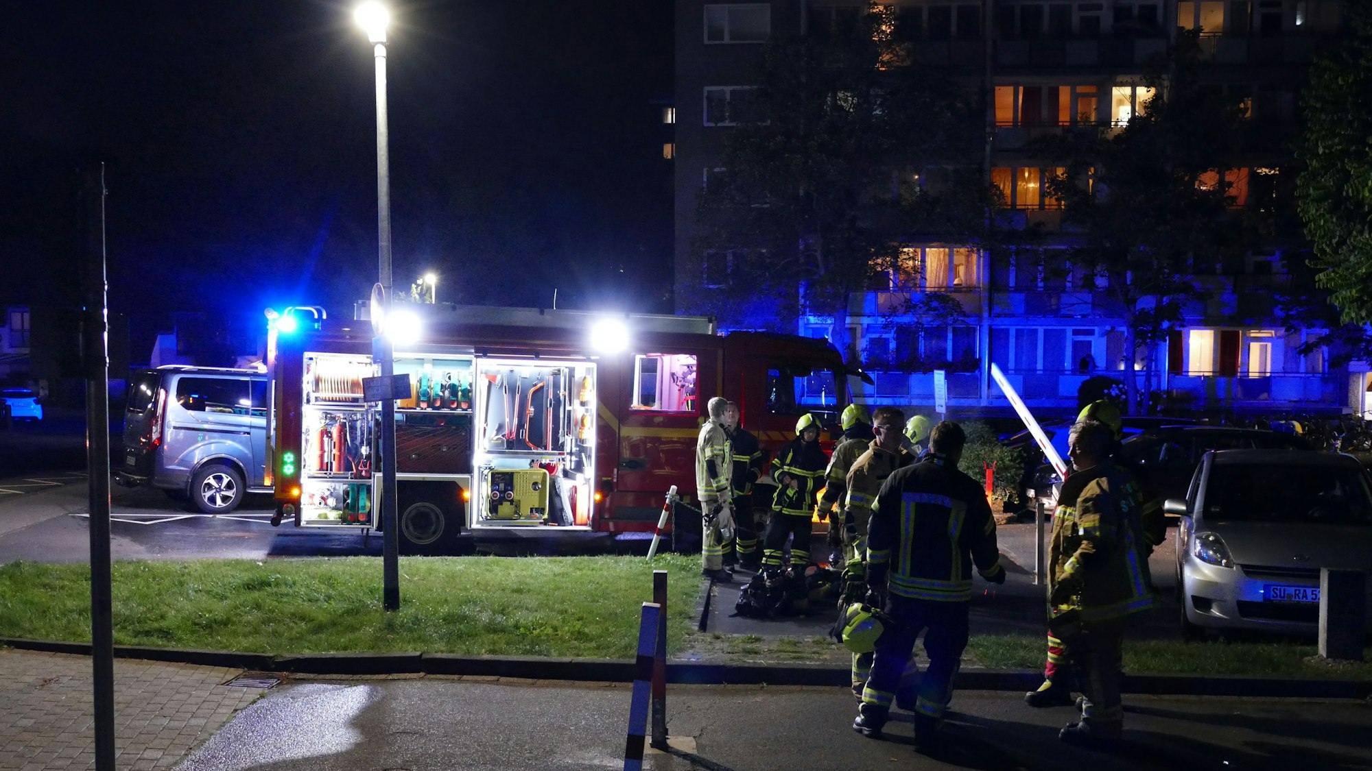 Feuerwehrleute stehen vor dem betroffenen Hochhaus in Niederpleis.