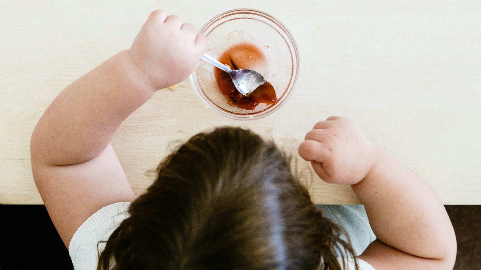 Ein übergewichtiges Kind von oben fotografiert, das gerade einen Nachtisch isst.