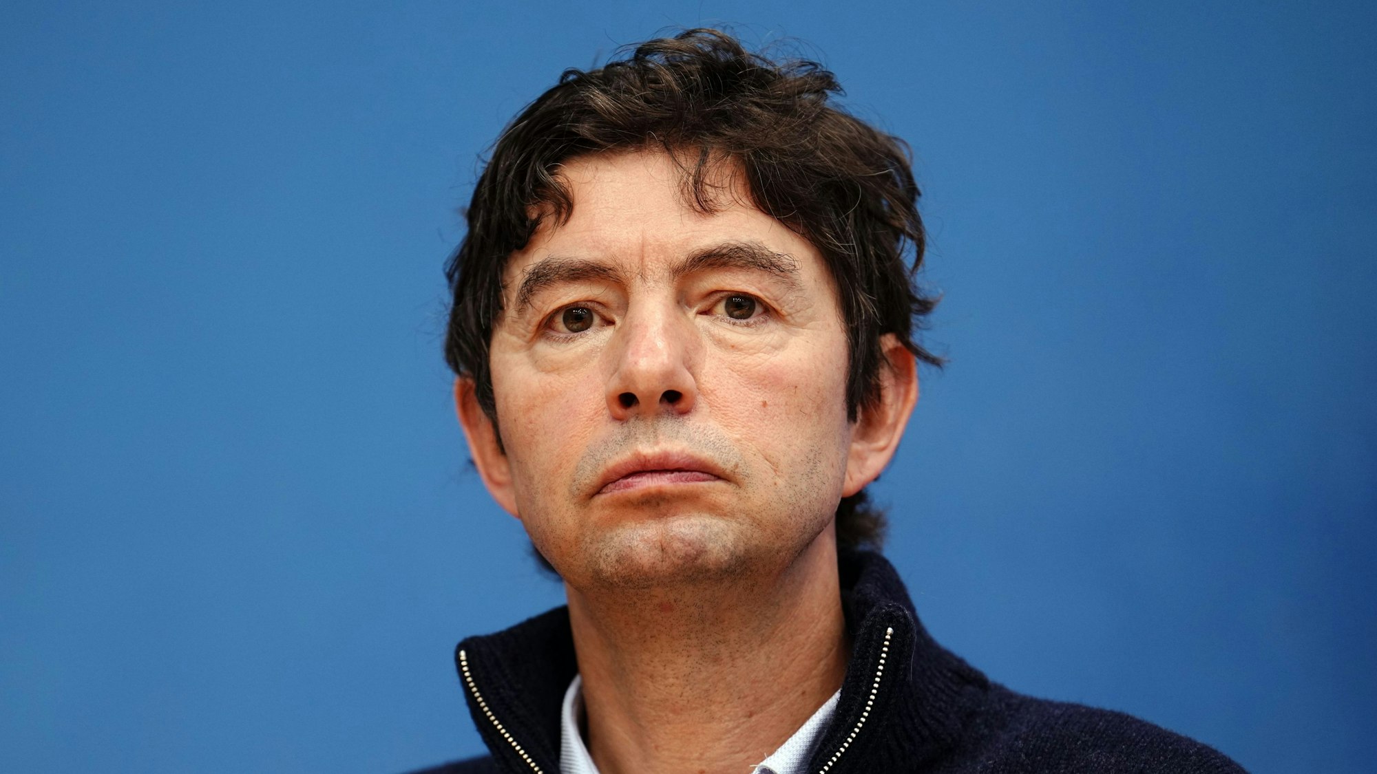 Virologe Christian Drosten, Direktor des Instituts für Virologie an der Berliner Charité, blickt auf einer Pressekonferenz vor einer blauen Wand in die Kamera.