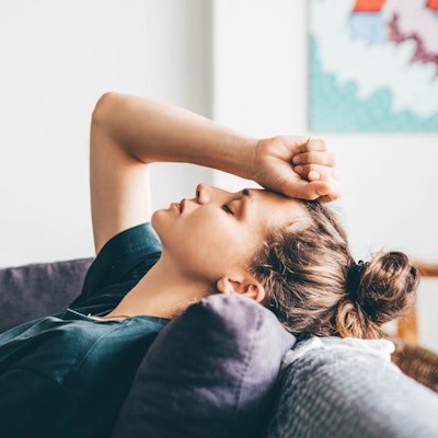 Frau verzweifelt, liegt zu Hause auf dem Sofa. Symbolbild