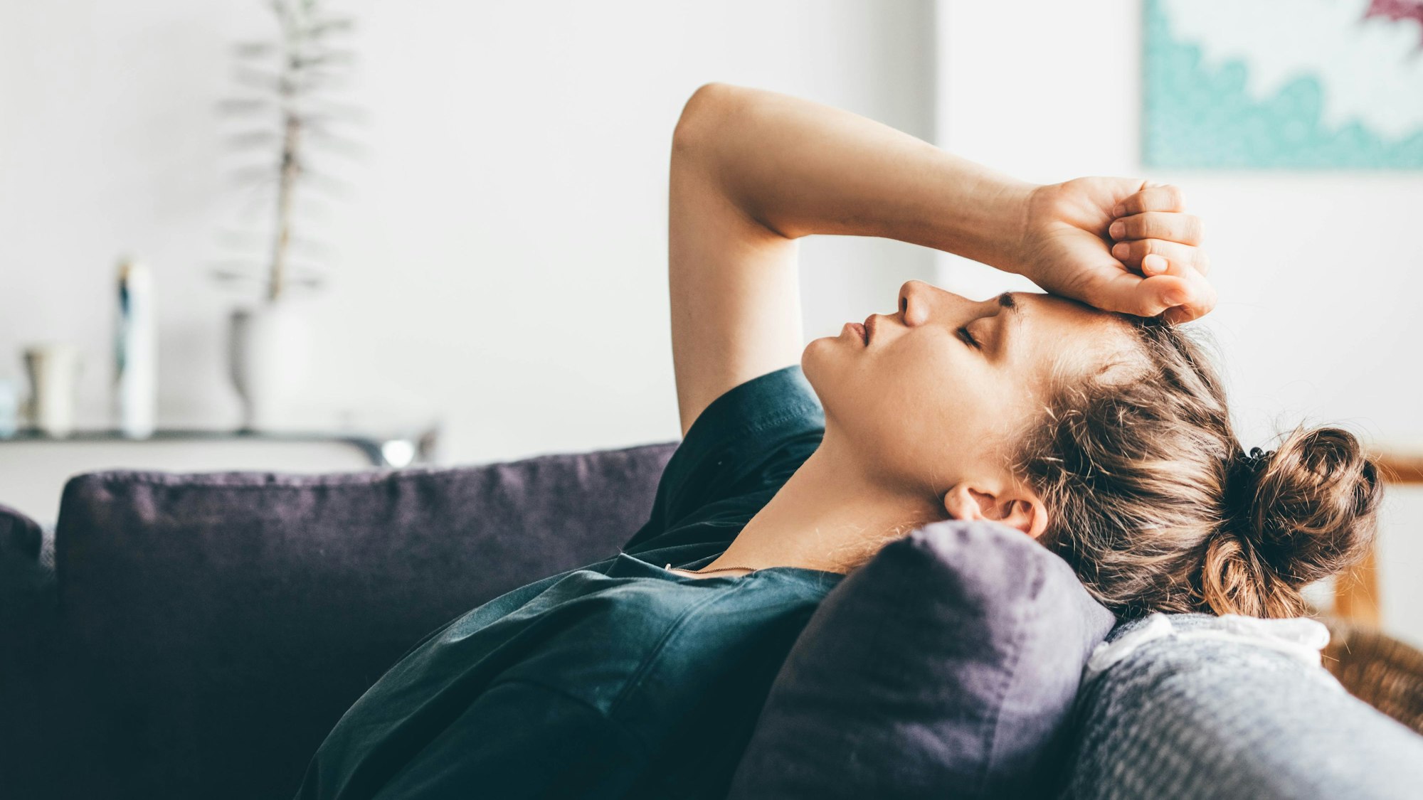 Frau verzweifelt, liegt zu Hause auf dem Sofa. Symbolbild