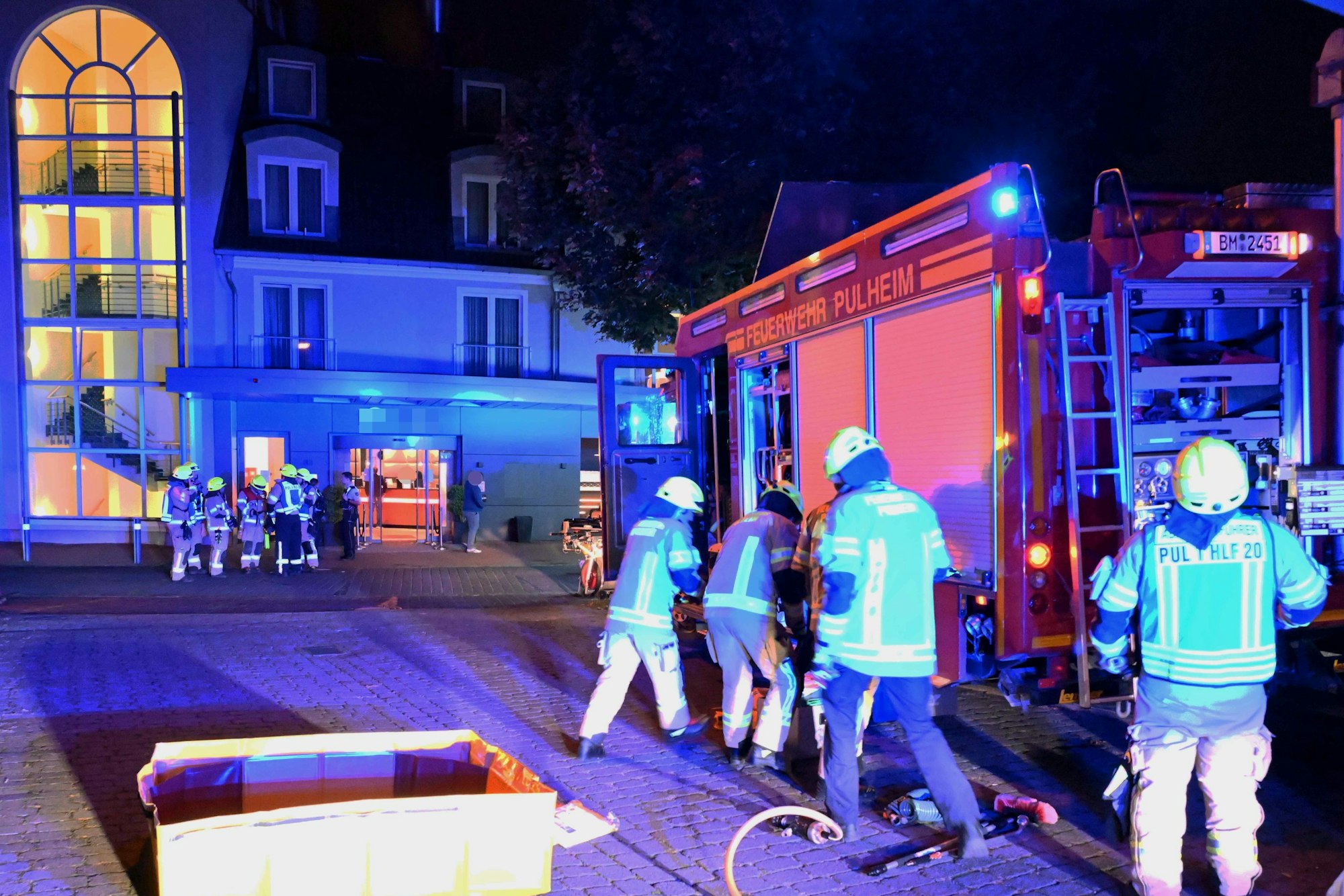Das Bild zeigt mehrere Einsatzkräfte an einem Feuerwehrfahrzeug vor dem Hotel.