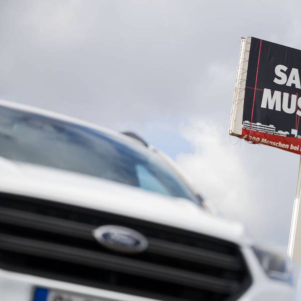 Ein Ford Kuga steht vor einem großen Schild, auf dem für die Bedeutung des Ford Werks in Saarlouis geworben wird.