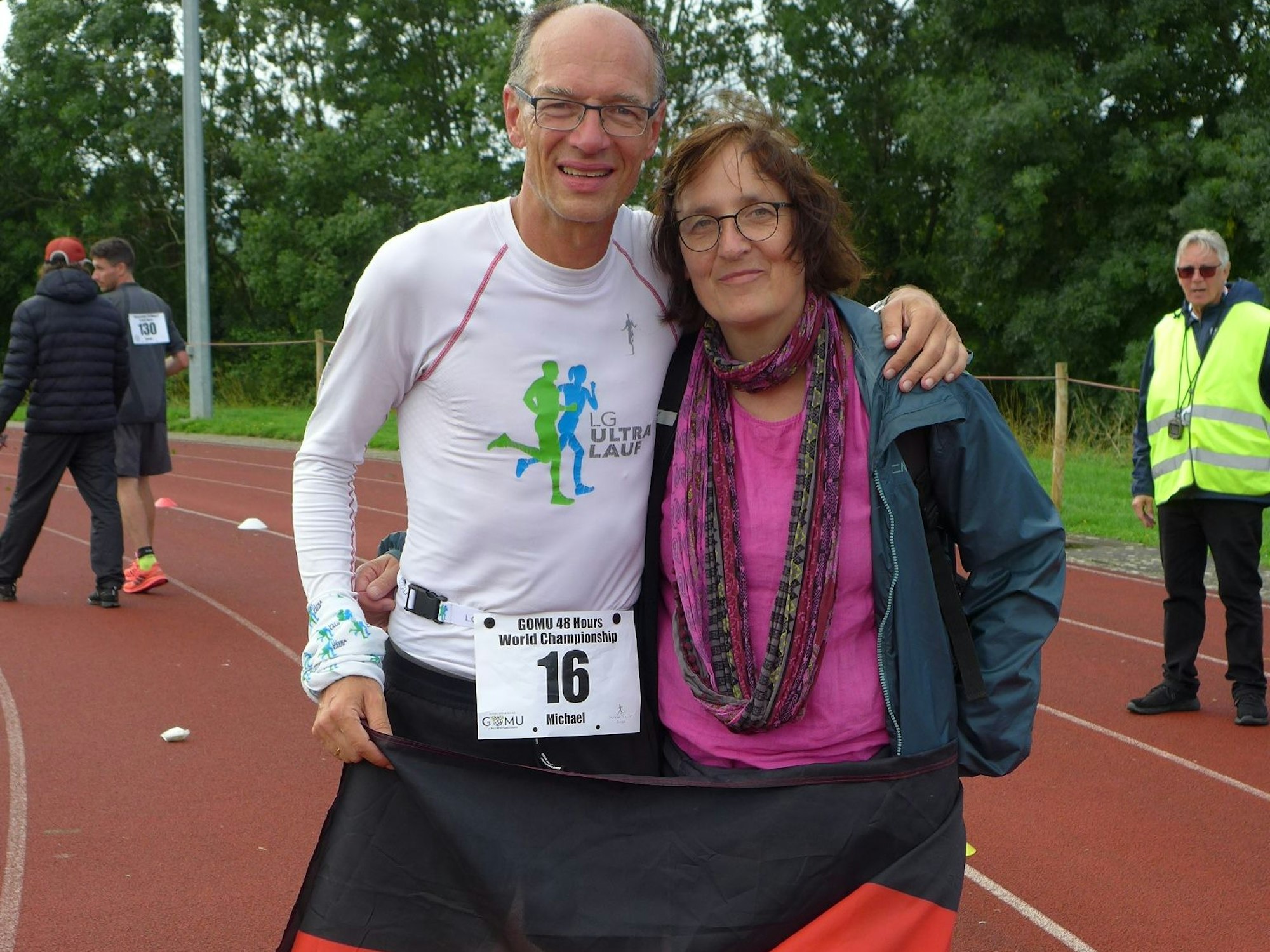 Ein Mann und eine Frau stehen mit der Deutschlandfahne Arm in Arm auf der Laufbahn.