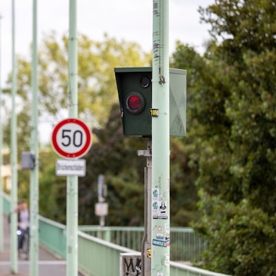 Ein Blitzer steht vor einem Schild, das auf Tempo 50 hinweist.
