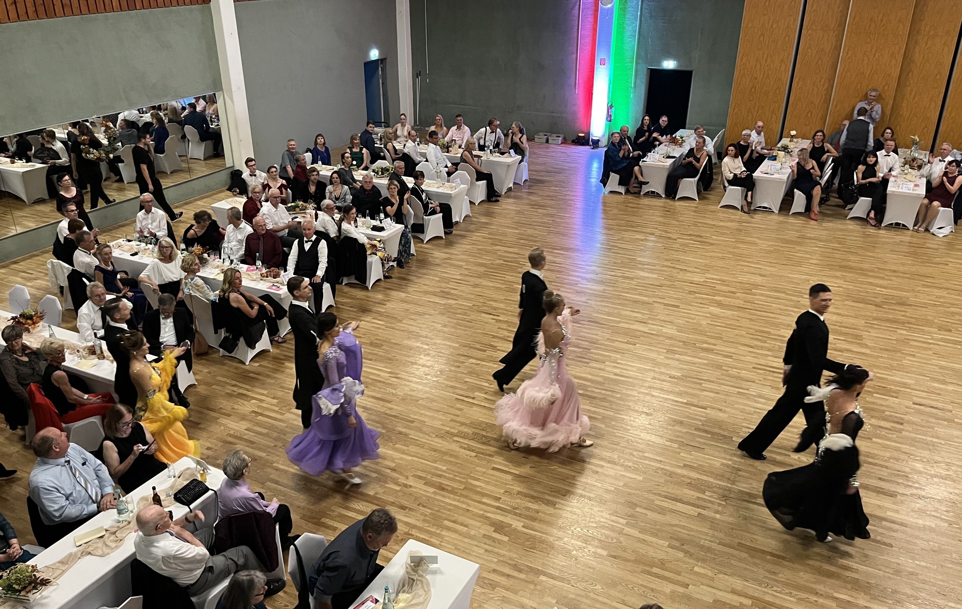 Tanzpaare laufen auf eine Tanzfläche aus Parkett.